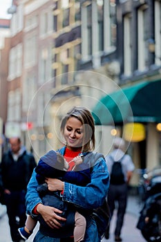 Girl with baby in carrier at street of Amsterdam