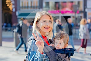 Girl with baby in carrier at street of Amsterdam