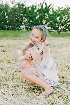 Girl with baby goat on farm outdoors. Love and care. Village animals. happy child hugs goat, concept of unity of nature