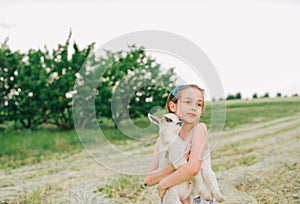 Girl with baby goat on farm outdoors. Love and care. Village animals. happy child hugs goat, concept of unity of nature