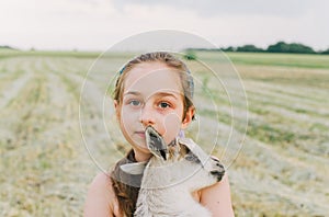 Girl with baby goat on farm outdoors. Love and care. Village animals. happy child hugs goat, concept of unity of nature