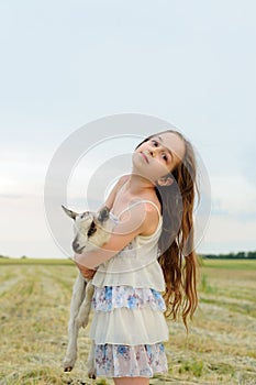 Girl with baby goat on farm outdoors. Village animals. happy child hugs goat, concept of unity of nature and man