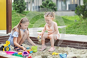 Girl and baby playing on sandbox. Toddler playing with sand molds and making mudpies