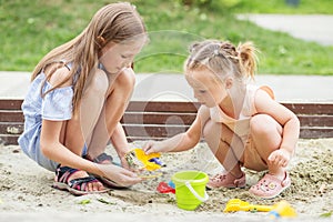 Girl and baby playing on sandbox. Toddler playing with sand molds and making mudpies