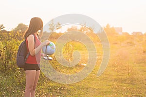 A girl with backback holding globe