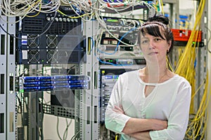 The girl is on a background of powerful data center datacenters. Portrait of a woman working as a system administrator in an