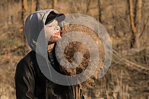 A girl on the background of reeds in the field, holding branches of reeds in her hand.