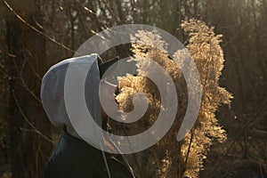 A girl on the background of reeds in the field, holding branches of reeds in her hand.