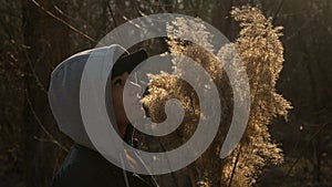 A girl on the background of reeds in the field, holding branches of reeds in her hand.