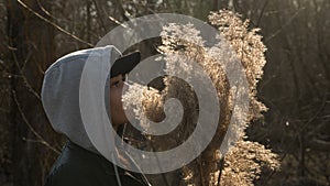 A girl on the background of reeds in the field, holding branches of reeds in her hand.