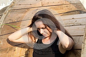 Girl on the background of a wooden reel for cable. Straightens hair with hands. Close-up portrait