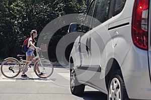 Girl with backpack and bike on pedestrian crossing