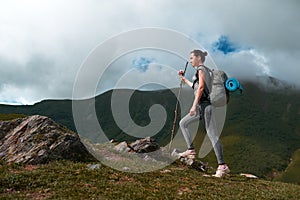 Girl with a backpack climbs on rocky mountain