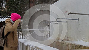 Girl with backpack drinks mineral water from hot springs in the resort of Arshan