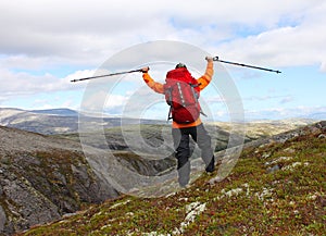 Girl with backpack standing on the mountain and rejoices