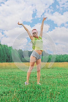 Girl with backpack standing outdoors with arms raised up to