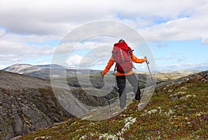 Girl with backpack standing on top of a mountain and looking at