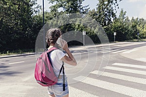 Girl using smartphone while walking through pedestrian crossing