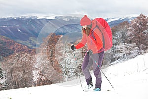 Girl with backpack walking on snow in the mountains.