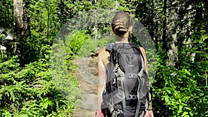 Girl with backpack walks along forest footpath