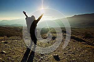 Girl-backpacker with hands up in the mountains