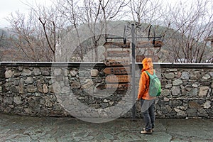 Girl-backpacker stands in front of pointers to the gift shops, horizontal