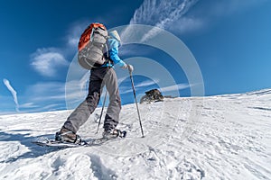 Girl backpacking with snowshoes in Alps on a sunny day, Saualpe range, Austria