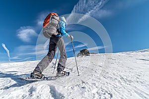 Girl backpacking with snowshoes in Alps on a sunny day, Saualpe range, Austria photo