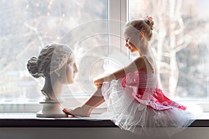 Girl ballerina in a tutu by the window