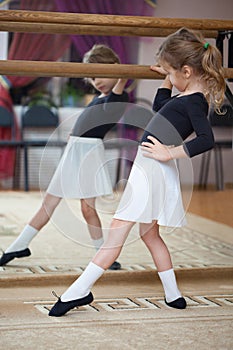 Girl at ballet barre. Ballet pas. Left profile.