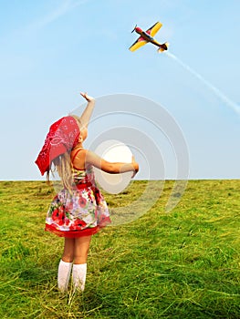 Girl with a balloon waving a hand flying aircraft.