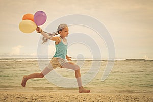 Girl with balloons jumping on the beach