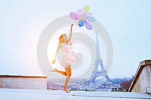 Girl with balloons jumping near Eiffel Tower in Paris