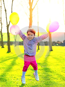 Girl with balloons jumping outdoor, at sunset