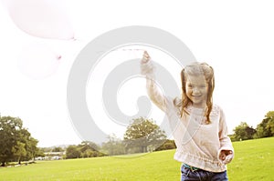 Girl with balloons in park.