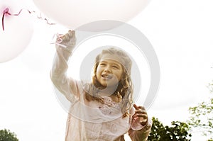 Girl with balloons in park.