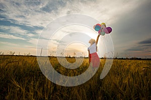 Girl with balloons in wheat field