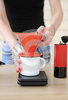 Girl barista brewing drip coffee in red pour over v60 hario close up without face. Manual grinder