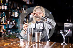 Girl barman formulates a cocktail in the taproom