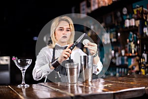 Girl barman formulates a cocktail in the taproom