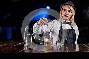 Girl barman makes a cocktail on the bar