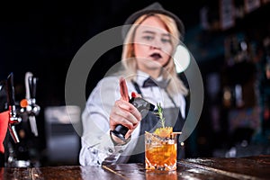 Girl bartender mixes a cocktail in the bar
