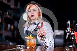 Girl bartender mixes a cocktail in the bar