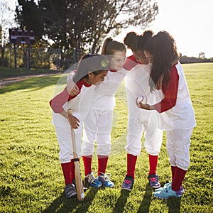 Girl baseball team in a team huddle, motivating before game