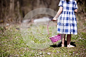 Girl with a  basket of the colorful Easter eggs on the green grass in a field