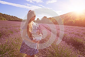 Girl with a basket of lavender flowers in a blooming lavender field, Provence, France