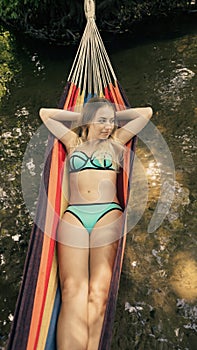 Girl in a bathing suit lying in a hammock over the water