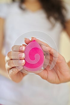 The girl in the bathroom, in a white t-shirt makes makeup with pink rosa beauty blender, woman holds a brush cosmetics, sponge