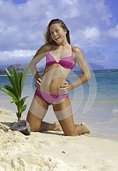Girl on beach with baby palm tree
