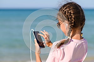 Girl on the beach listens to music.